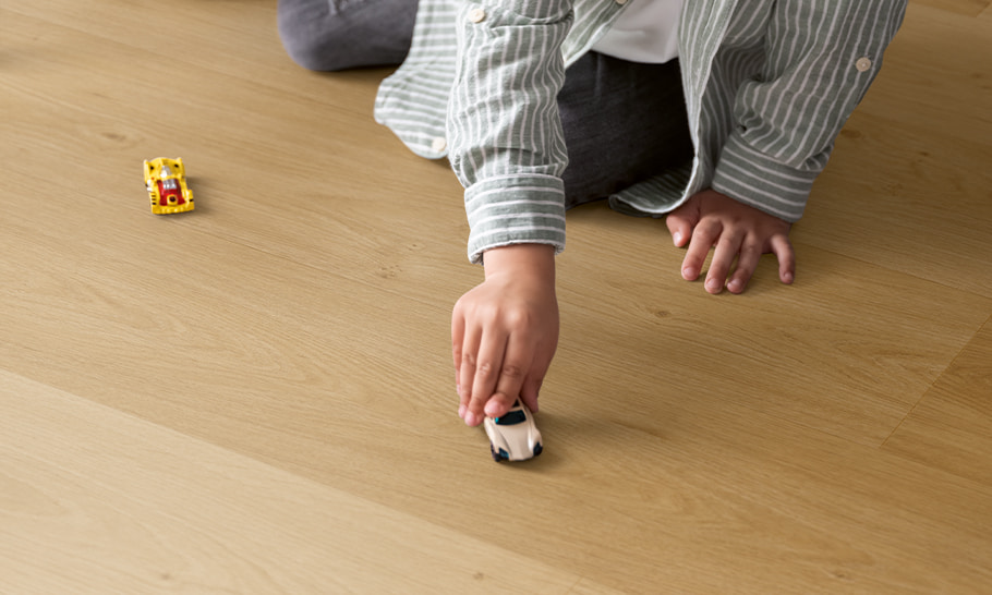 kid playing with toy car on a beige vinyl floor